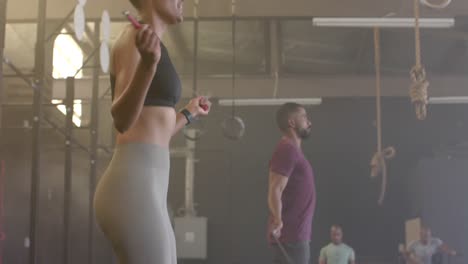 hombre y mujer diversos entrenando en el gimnasio saltando la cuerda, en cámara lenta