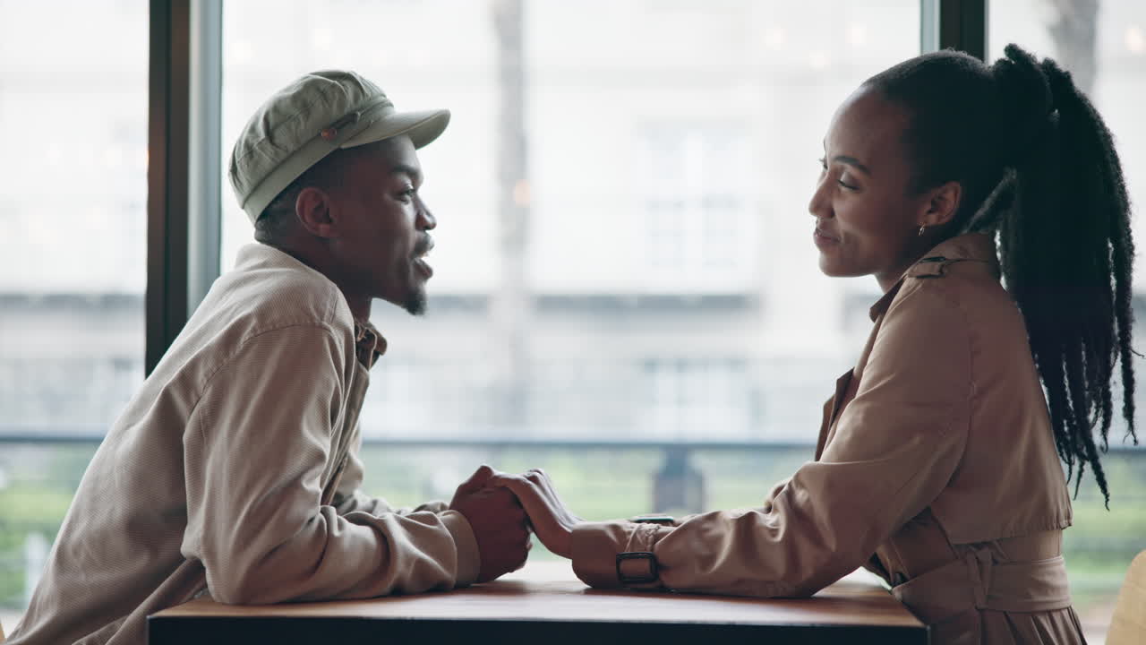 Couple, laughing and holding hands on table