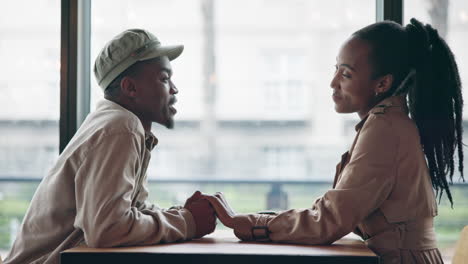 couple, laughing and holding hands on table