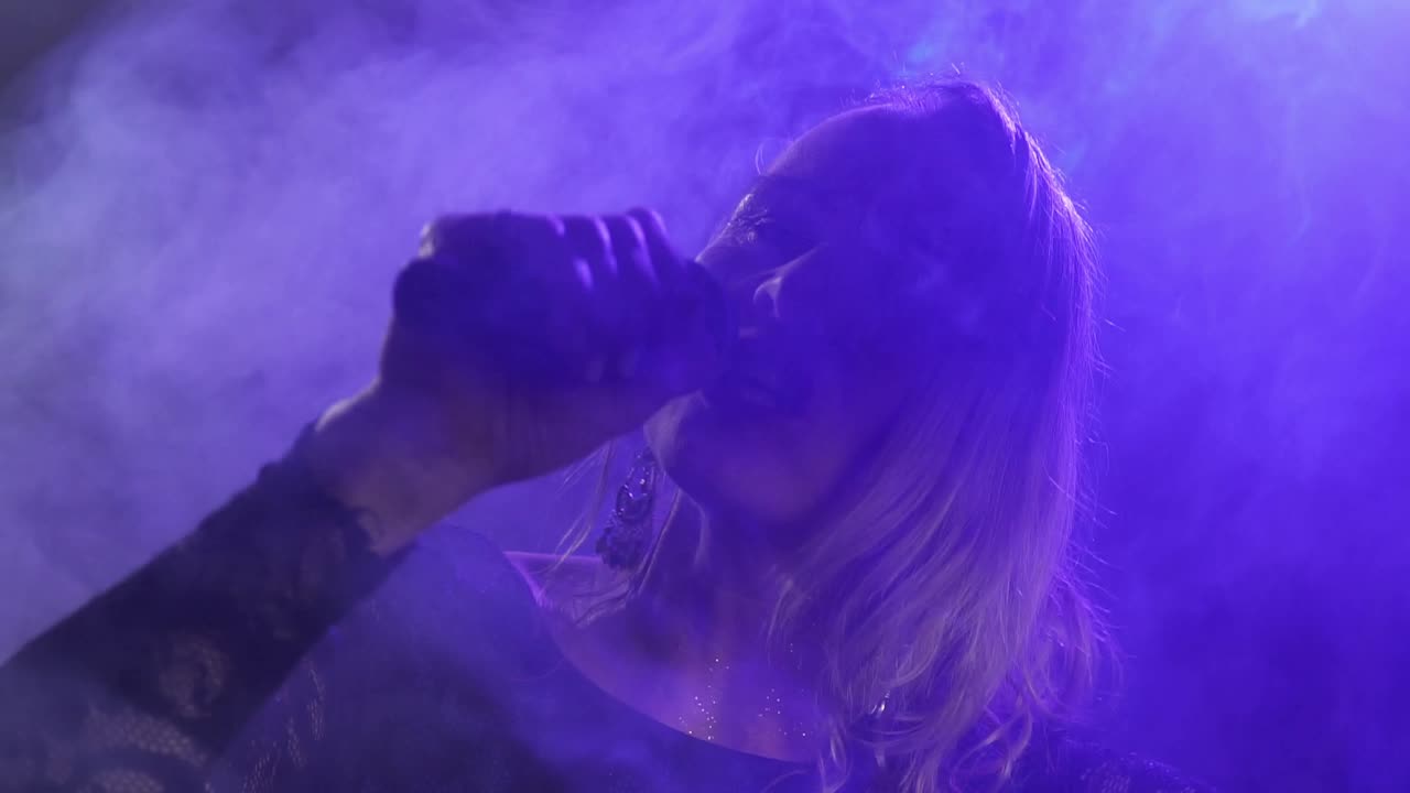 Mature blonde female vocalist singing with a microphone on a stage