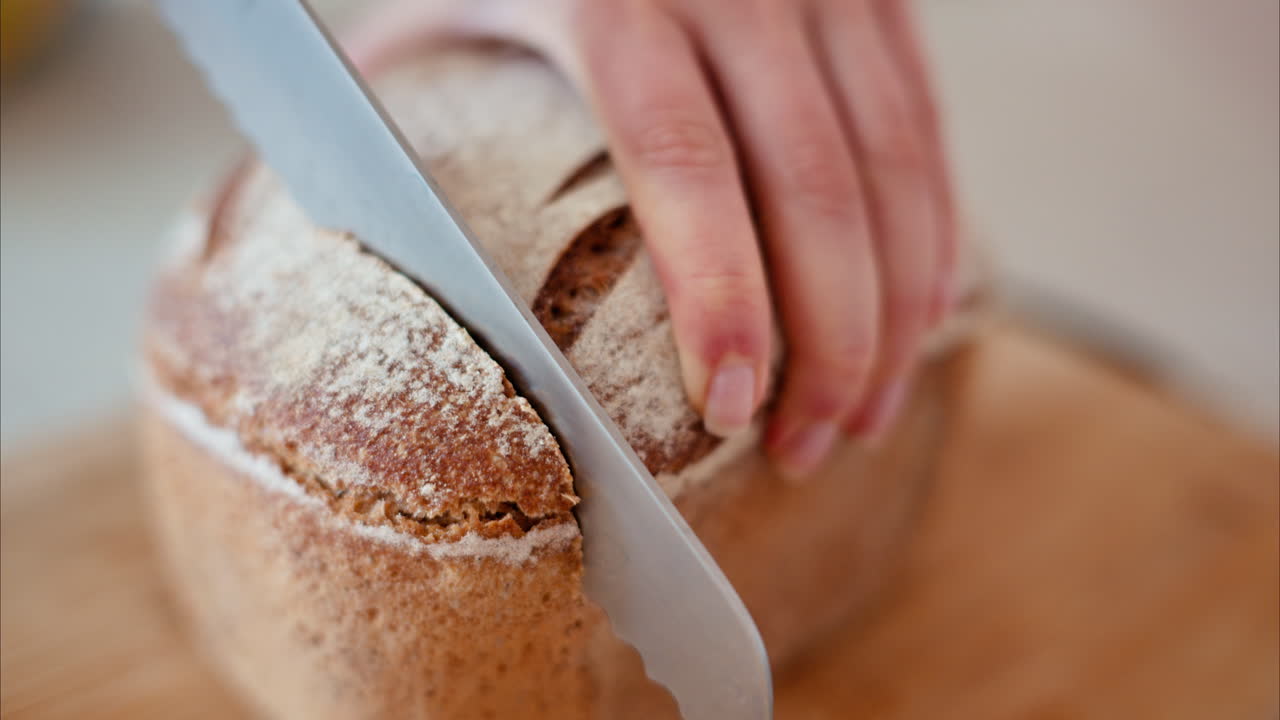 Woman cutting rye sourdough bread on a wooden cutting board