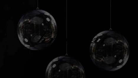 Animation-of-gold-glowing-christmas-text-over-christmas-decorations-baubles-on-black-background