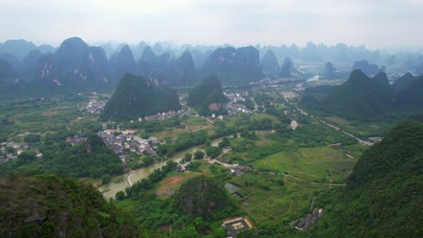 Drone-flying-over-the-lush-green-karst-mountains-of-Yangshuo,-China