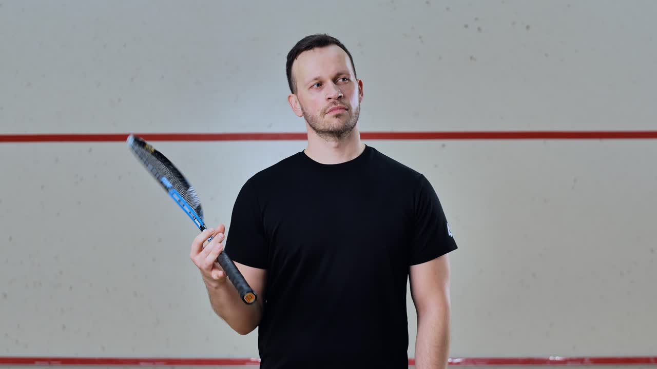 Slow motion pro squash player spinning racket calmly before intense match begins