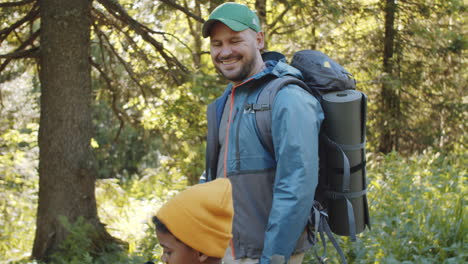 una alegre familia multiétnica haciendo senderismo en el bosque en un día soleado