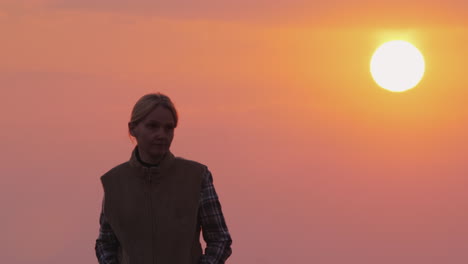 Una-Mujer-Avanza-Contra-El-Cielo-Rosado-Y-El-Sol-Poniente