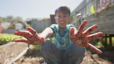 Retrato-De-Un-Niño-Birracial-Feliz-Mostrando-Las-Manos-Cubiertas-De-Tierra,-Cámara-Lenta,-Espacio-De-Copia