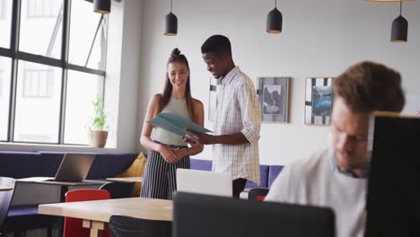 Happy-diverse-business-people-discussing-work-during-meeting-at-office