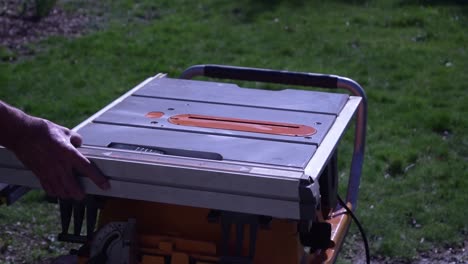 a close-up of a man securing his portable table saw with a safety-guard