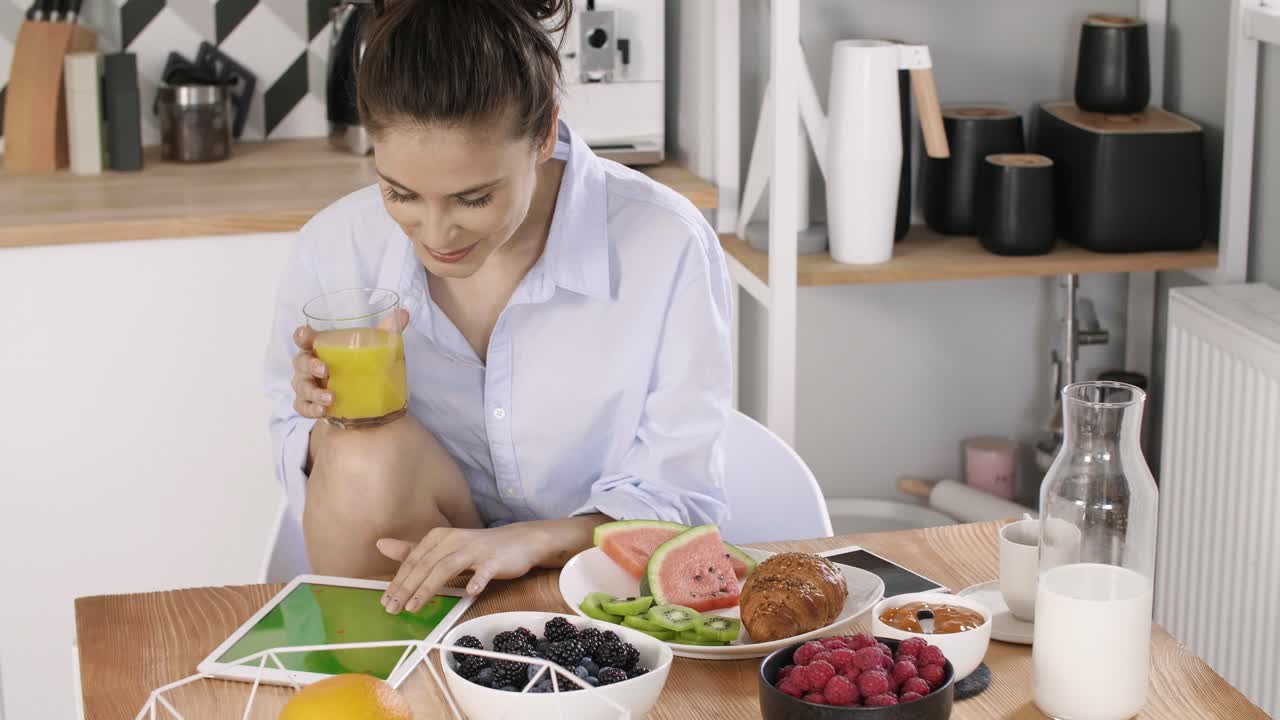 mujer joven usando una tableta durante el desayuno