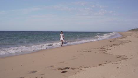 Joven-Caminando-Por-La-Orilla-Arenosa-De-La-Playa-En-Bunbury,-Australia---Plano-Amplio