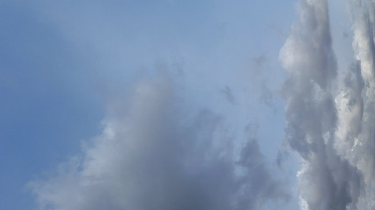 세로 형식:타임랩스에서 극적인 비구름이 옅은 푸른 하늘을 가로지릅니다.