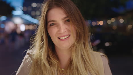 retrato de cerca de una hermosa mujer rubia sonriendo a la cámara disfrutando de una hermosa noche urbana