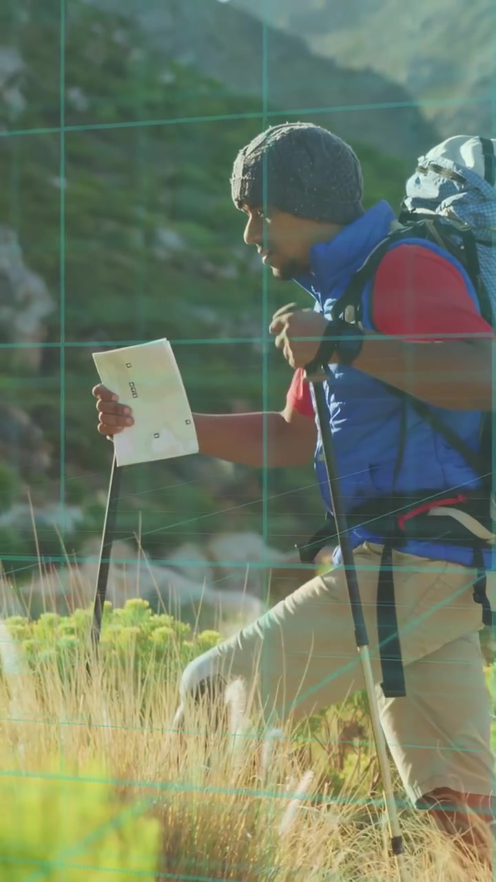 Vertical video: Hiker scanning map then planting poles while navigating outdoor meadow toward ridge