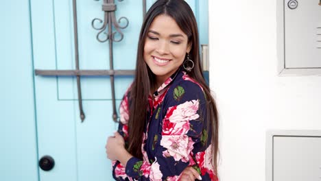 mujer con camisa floral por una puerta azul