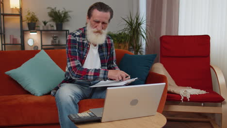 hombre de contabilidad pagos calculando gastos mensuales facturas bancarias, analizando el papeleo en casa