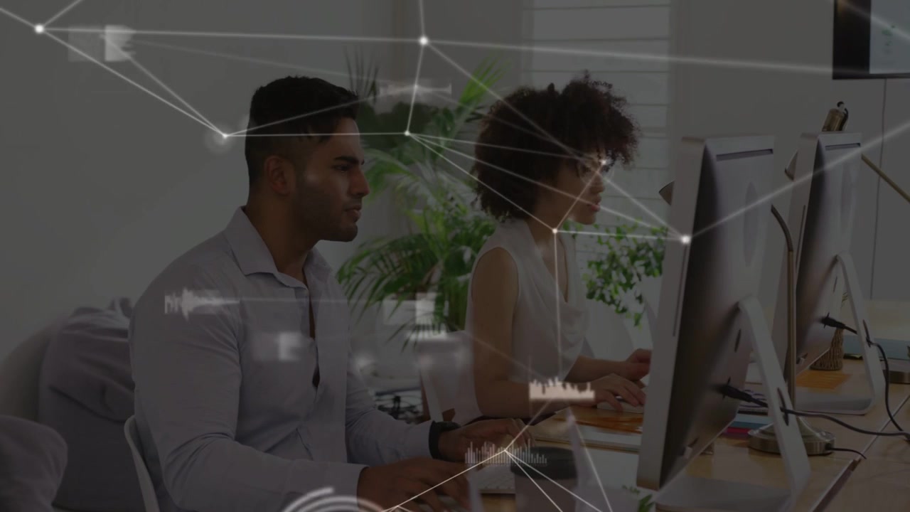 Coworker duo typing and collaborating in tech hub, initiating network overlay across screens