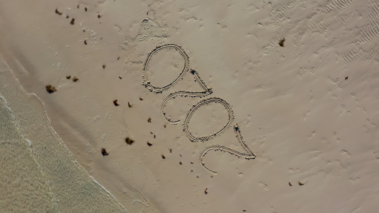 해변의 모래에 쓰여진 2020을 보여주는 오름차순으로 똑바로 내려다보는 항공 카메라