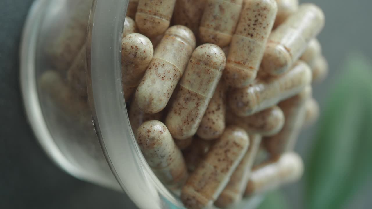 Close-up of numerous natural supplement capsules in a clear bottle