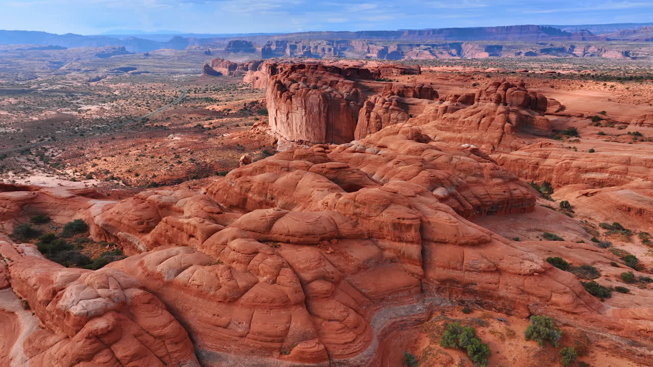Rocce rosse arrotondate e spoglie con alcuni arbusti che crescono alla base. Canyon stravaganti nell'Arches National Park nello Utah, USA. Prospettiva aerea