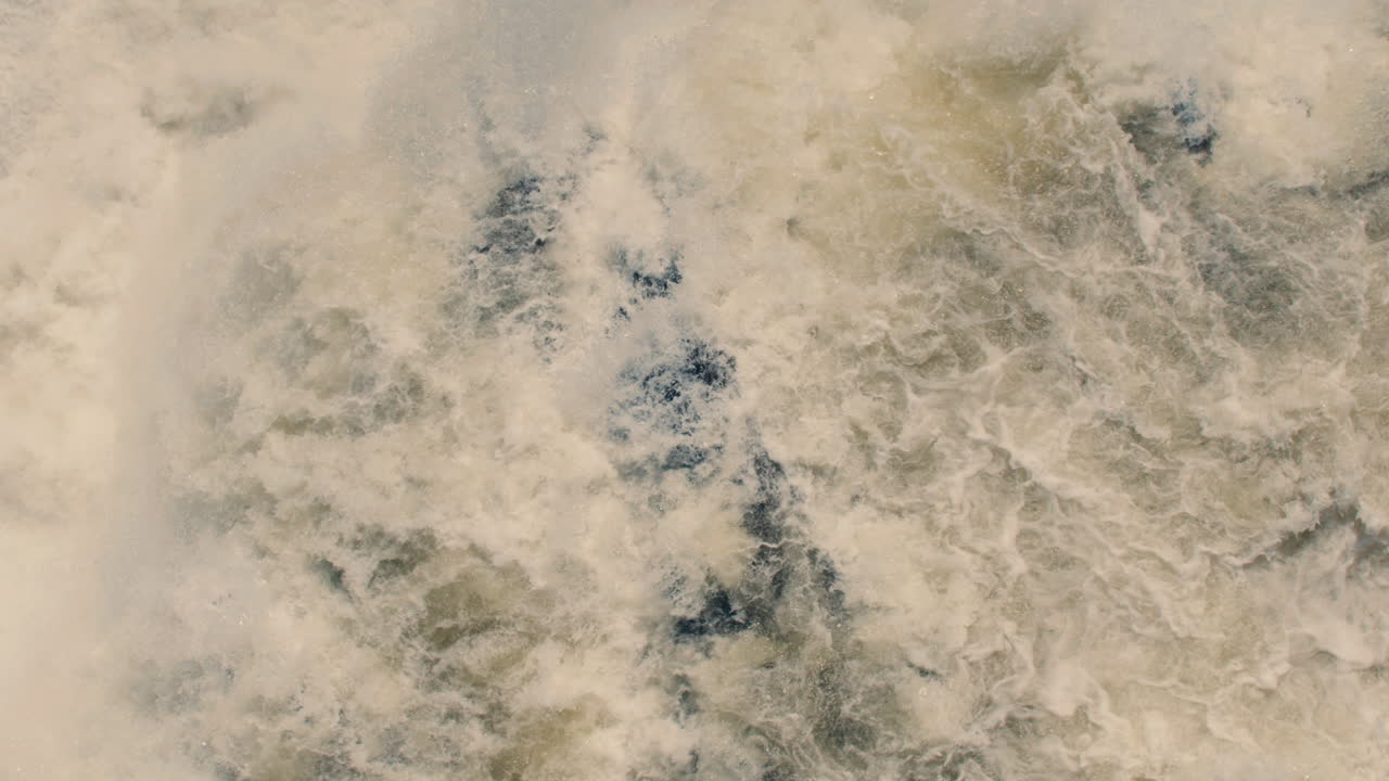 Aerial view of white water rushing down river and waterfall in slow motion 40fps