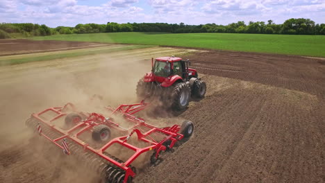 Agricultural-tractor-with-trailer-plowing-on-farming-field.-Farming-machinery