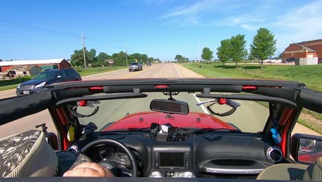 pov driving on a paved road in rural south dakota, wind catching drivers hat