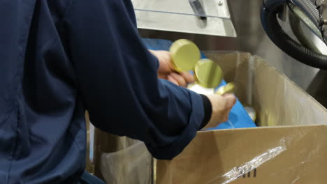 blue caps being mechanically lined in factory setting, worker overseeing process and inspecting the product