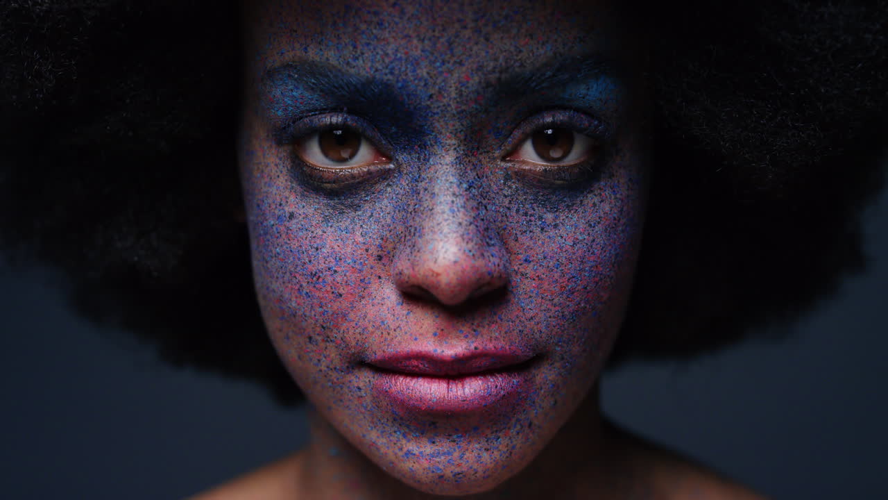 retrato de cerca de una hermosa mujer afroamericana que usa pintura exótica para la cara arte corporal mujer misteriosa con maquillaje colorido luz parpadeante en fondo oscuro concepto de expresión creativa