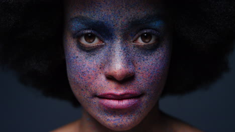 retrato de cerca de una hermosa mujer afroamericana que usa pintura exótica para la cara arte corporal mujer misteriosa con maquillaje colorido luz parpadeante en fondo oscuro concepto de expresión creativa