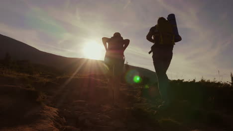 Silhouetten-Ein-Paar-Touristen,-Die-In-Den-Strahlen-Der-Untergehenden-Sonne-Einen-Berg-Besteigen,-Rückansicht-Konzept