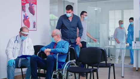 invalid old man with face mask discussing with doctor in hospital waiting area