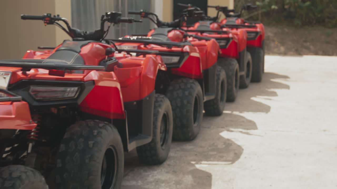 A group of red ATVs parked in line under daylight, ready for an offroad adventure tour.