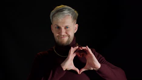 Hombre-Sonriente-Y-Elegante-Con-Ojos-Azules-Mostrando-Forma-De-Corazón-Con-Las-Manos-En-Forma-De-Corazón,-Bondad-Humana