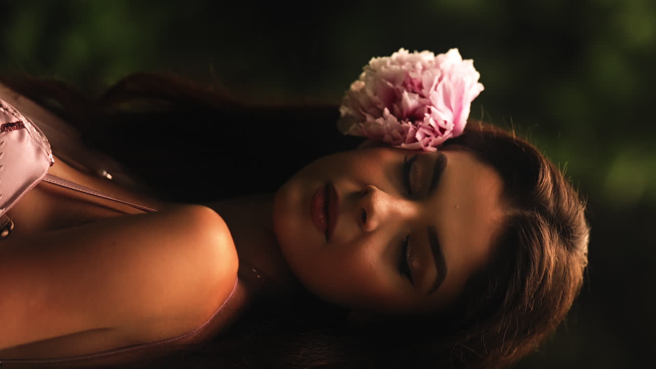 Ritratto verticale di una bella ragazza con un fiore rosa dietro l'orecchio