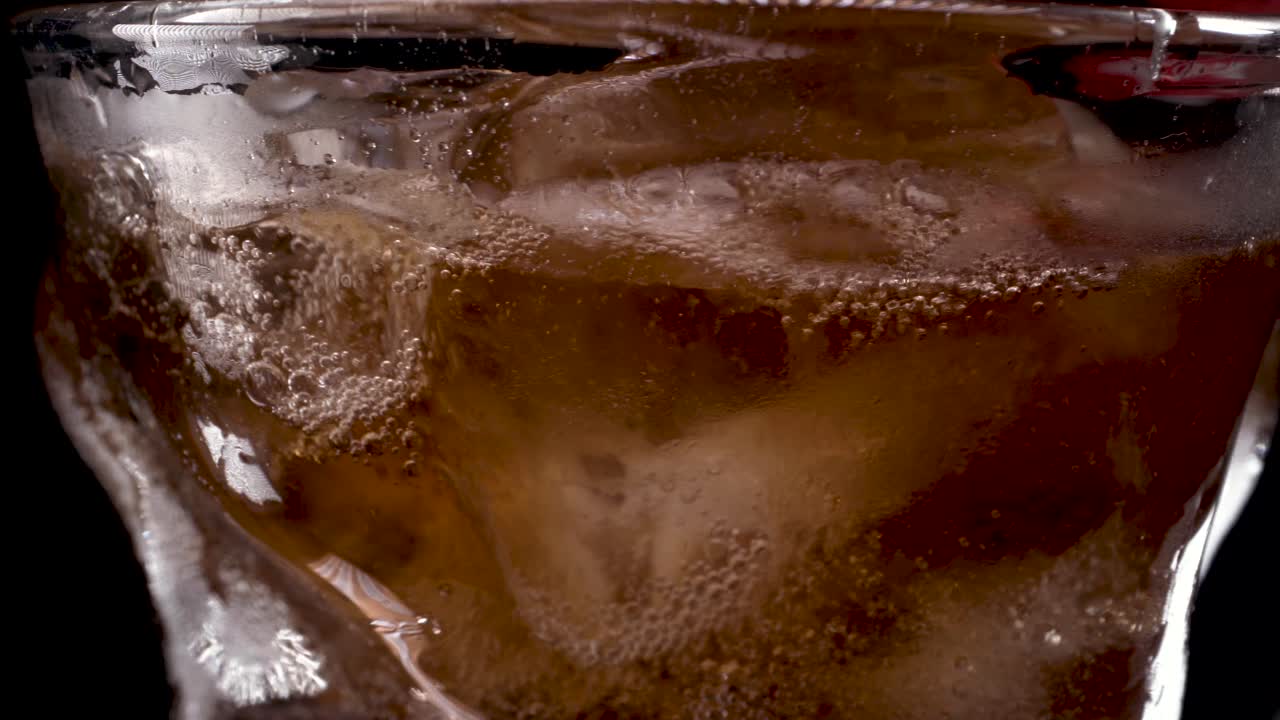 cola y hielo en vaso, cola vertida en un vaso con curvas con cubitos de hielo