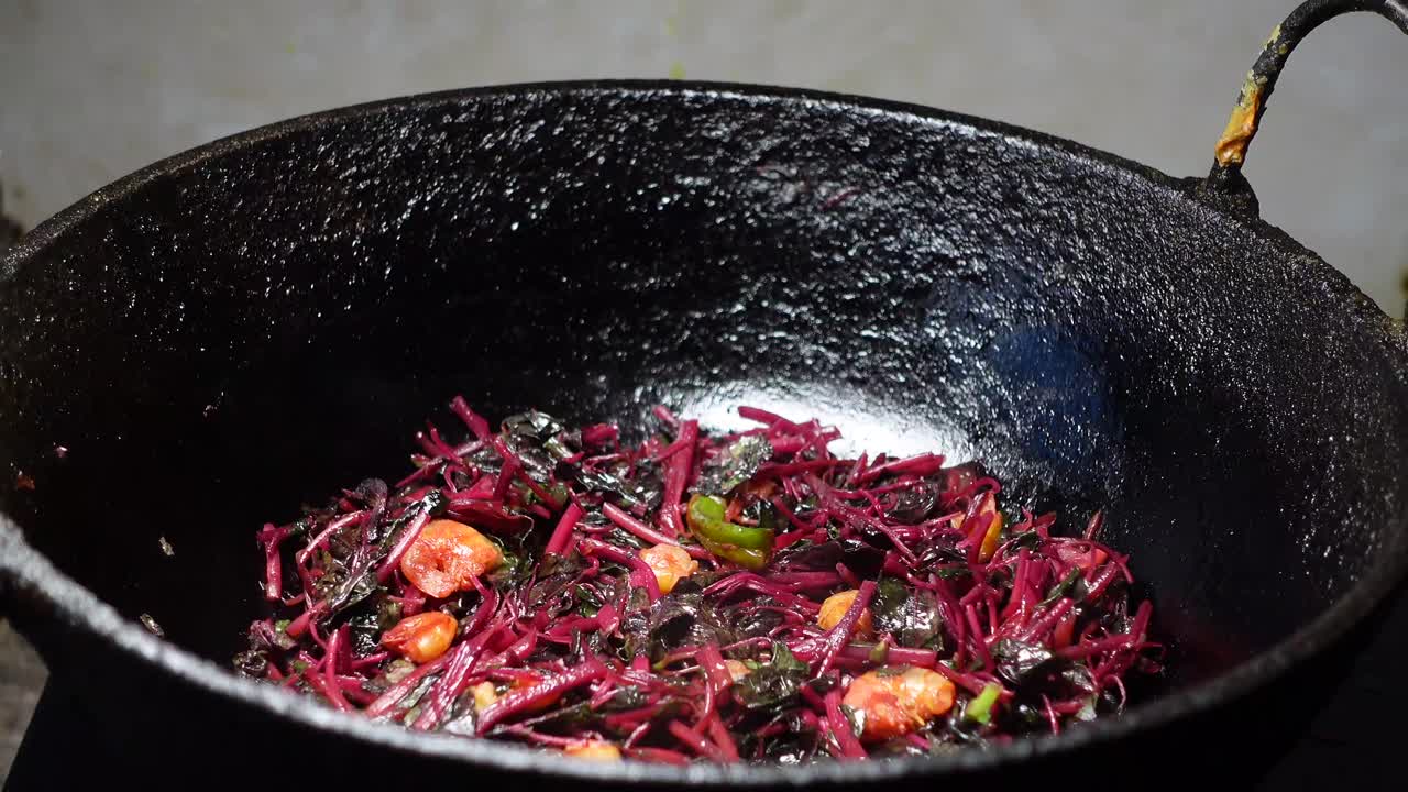 Cooking a Stir-Fry with Reddish-Purple Leaves and Shrimp in a Cast Iron Pan