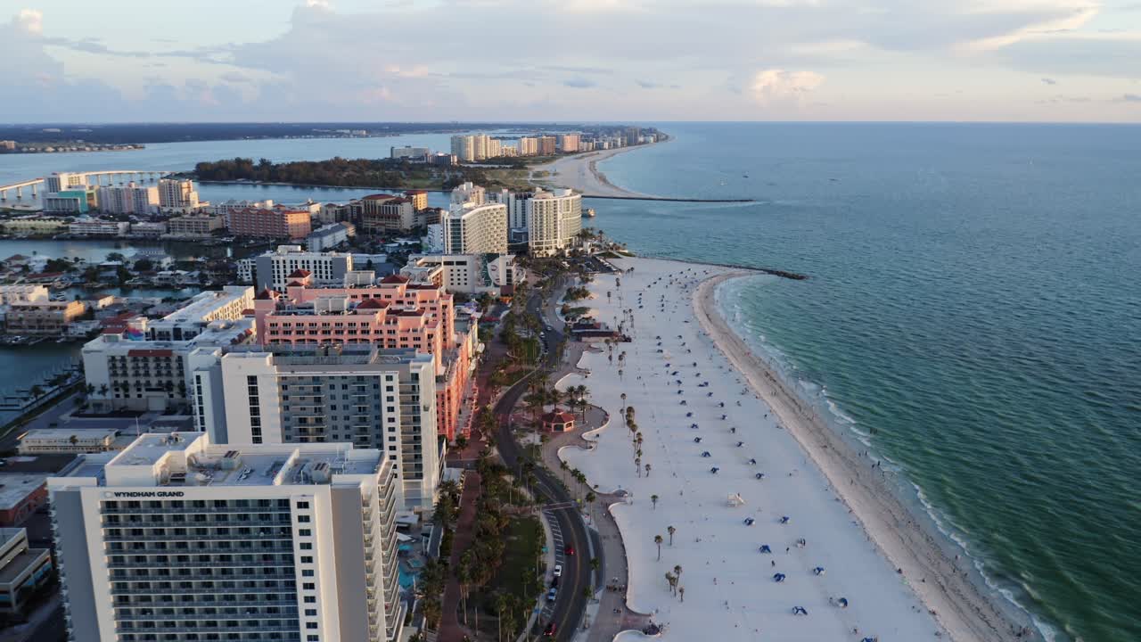 High-rise resorts tower above the bright white sands of Clearwater Beach, where umbrellas dot the shoreline beside the calm blue waters of the Gulf of Mexico