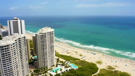 Aerial-drone-shot-slowly-rotating-clockwise-around-buildings-including-the-Ritz-Carlton-residences-looking-out-toward-the-beach-and-Atlantic-ocean-on-a-sunny-day-with-blue-skies