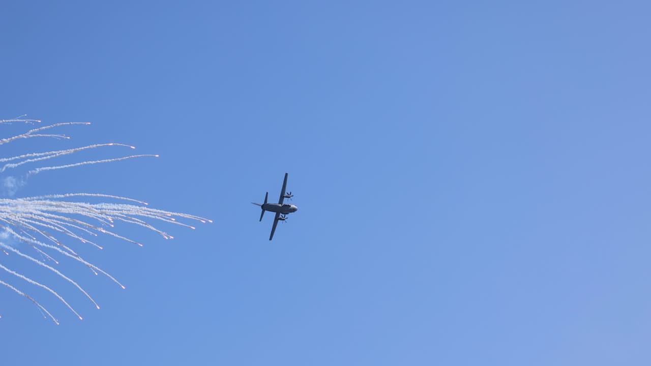 A military aircraft performs aerobatic maneuvers, releasing flares against a clear blue sky during an airshow in Geelong, Australia