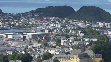 panoramic establishing shot of ålesund, norway, from fjellstua viewpoint, showcasing its colorful architecture nestled between forested hills, overlooking serene waterways and distant islands