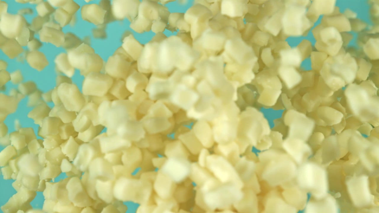 Diced Cheese Cubes Floating Against a Blue Background