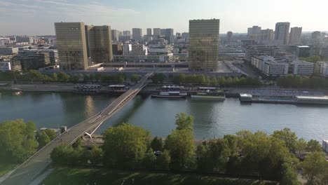 passerelle simone-de-beauvoir or bercy-tolbiac, pedestrians and cyclists bridge on seine river with francois mitterrand national library in background, paris in france