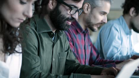 side view of smiling developer in eyeglasses working with laptop