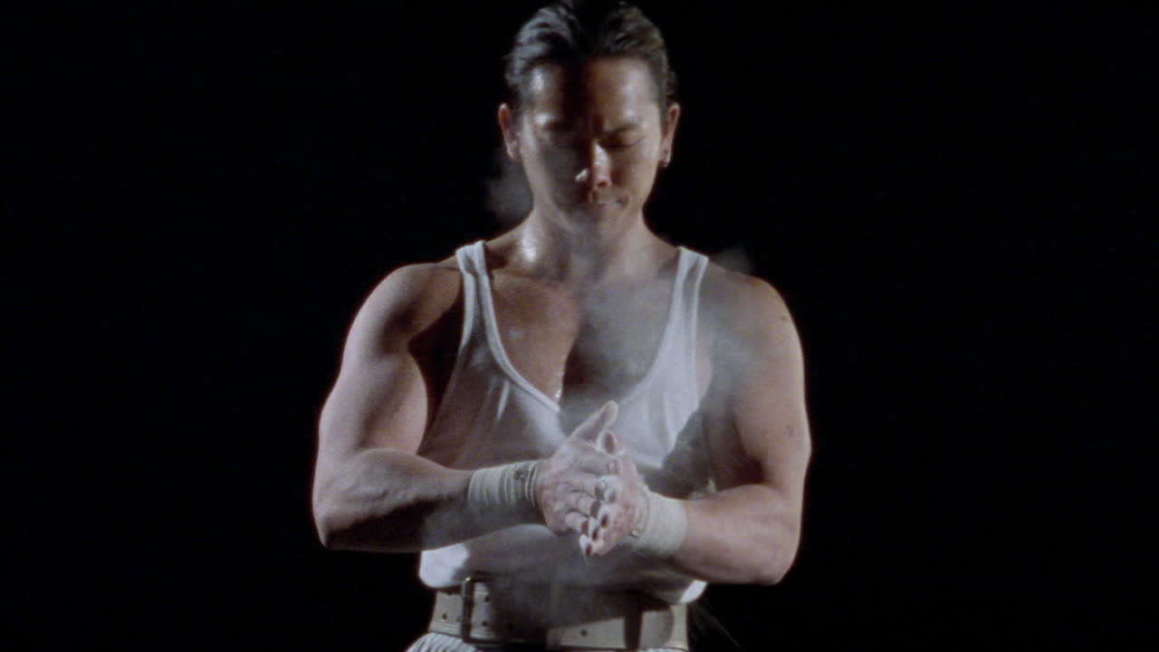 un hombre se pone polvo en las manos y luego levanta una pesa sobre su cabeza