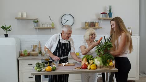 elderly couple in kitchen receiving vegetables from grandchild. raw food healthy eating diet