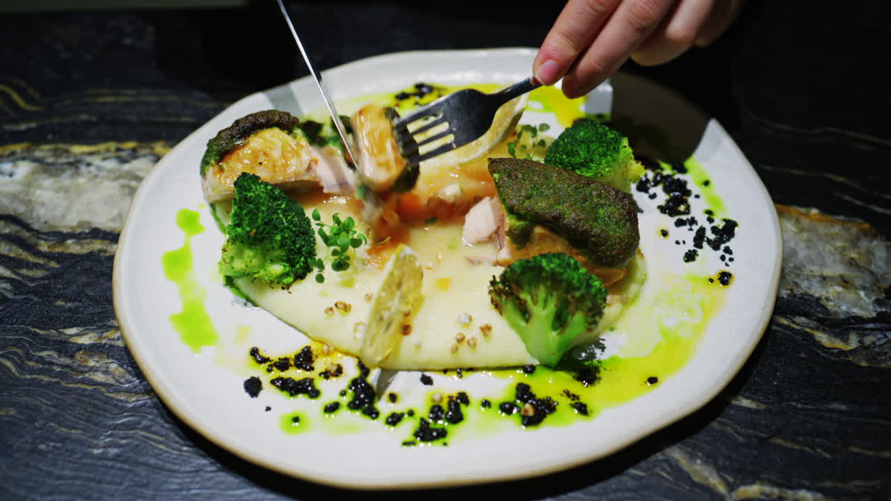 Fine dining plated fish dish with broccoli, creamy puree, herbs, and green sauce
