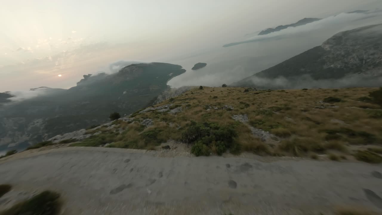 FPV Aerial drone forward moving shot over winding road over mountain range along seaside in Mallorca Albercutx Formentor, Balearic Islands, Spain on a cloudy day
