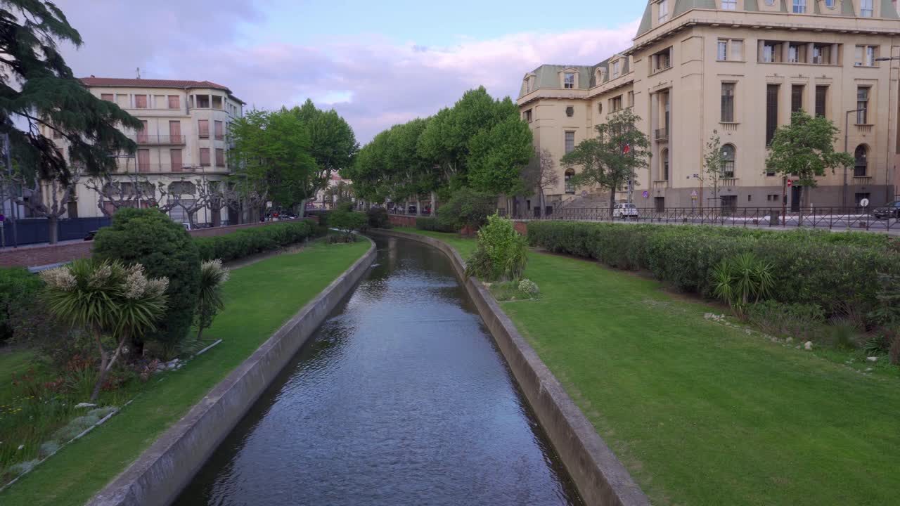 mirando a lo largo de un canal en el centro de la ciudad de perpiñán en un día caluroso pero ventoso a principios de verano