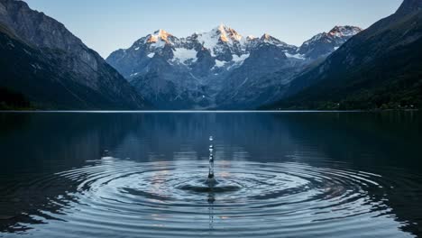 the tranquil surface of the lake captures the beauty of majestic mountain peaks, their reflections dancing in the rippling water at dawn